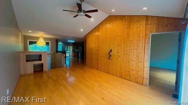 45903 Dutton Dr, Shelby Twp, MI 48044 - unfurnished living room with a ceiling fan, vaulted ceiling, wood walls, wood finished floors, and a fireplace