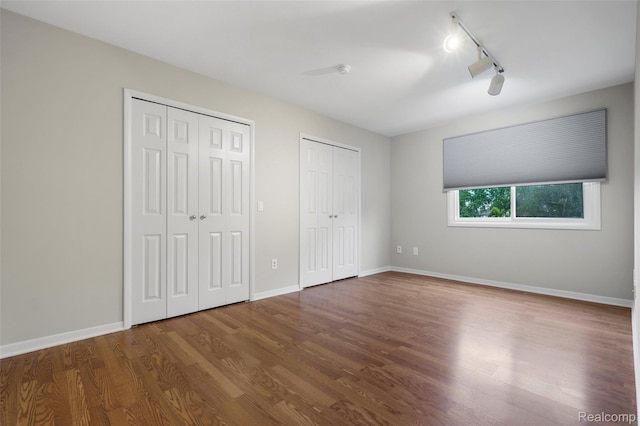 890 Darwin Place Ct, Rochester Hills, MI 48307 - unfurnished bedroom featuring multiple closets, track lighting, wood finished floors, and a ceiling fan