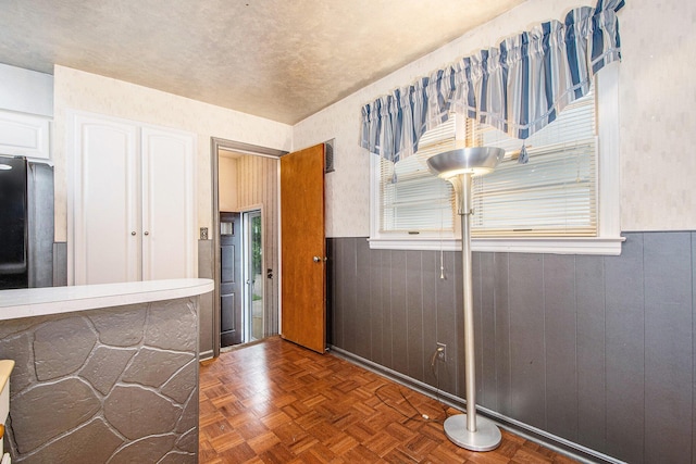 2736 Cascade Rd SE, Grand Rapids, MI 49506 - kitchen featuring wainscoting, freestanding refrigerator, white cabinetry, and wooden walls