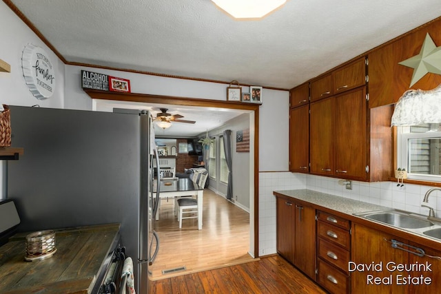730 S 160th Ave, Holland, MI 49423 - kitchen featuring dark wood-type flooring, a ceiling fan, brown cabinets, freestanding refrigerator, and ornamental molding