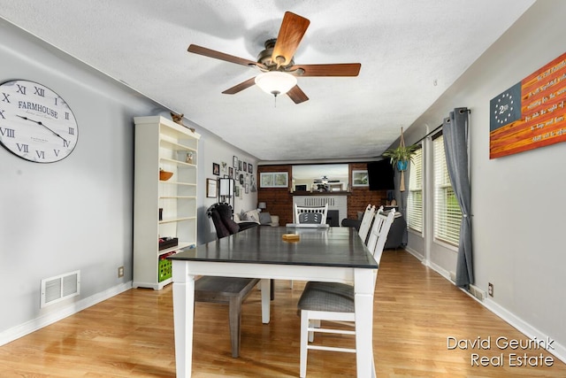 730 S 160th Ave, Holland, MI 49423 - dining space with ceiling fan, a fireplace, light wood-style floors, and a textured ceiling
