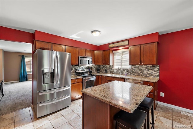 16322 Canterbury Ct, Macomb, MI 48044 - kitchen featuring stainless steel appliances, decorative backsplash, light stone countertops, a kitchen island, and a breakfast bar