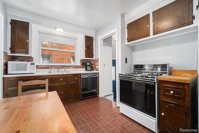 20874 Woodmont St, Harper Woods, MI 48225 - kitchen featuring gas stove, black dishwasher, wooden counters, white microwave, and brick patterned floors