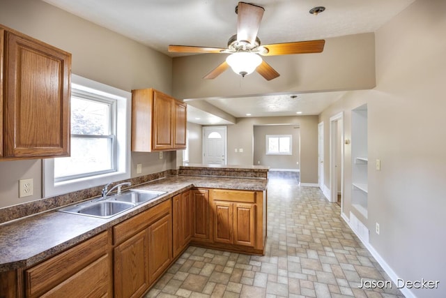 1440 College Ave NE, Grand Rapids, MI 49505 - kitchen with a peninsula, dark countertops, brown cabinetry, and ceiling fan