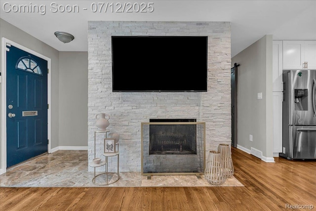 19425 Butternut Ln, Southfield, MI 48076 - unfurnished living room featuring wood finished floors and a stone fireplace