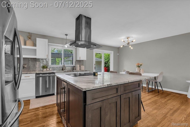 19425 Butternut Ln, Southfield, MI 48076 - kitchen with appliances with stainless steel finishes, island exhaust hood, white cabinetry, light wood finished floors, and tasteful backsplash