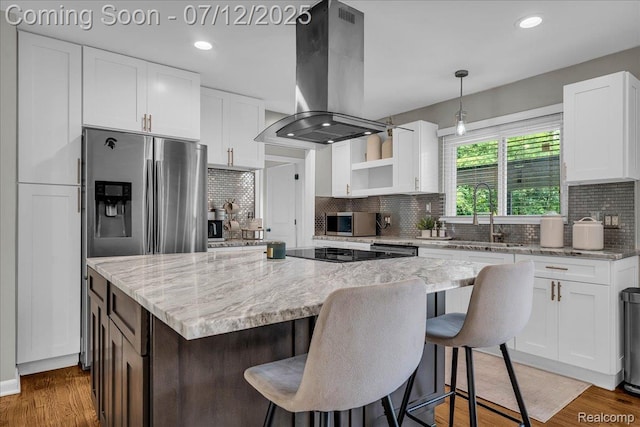 19425 Butternut Ln, Southfield, MI 48076 - kitchen featuring island range hood, appliances with stainless steel finishes, a kitchen island, tasteful backsplash, and white cabinets