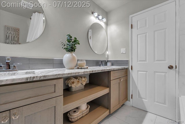 19425 Butternut Ln, Southfield, MI 48076 - bathroom featuring double vanity, marble look tile flooring, and a wainscoted wall