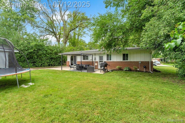 19425 Butternut Ln, Southfield, MI 48076 - back of property featuring a trampoline, a patio, outdoor lounge area, brick siding, and a lawn