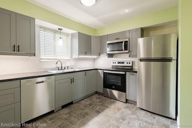 3782 Egan St, Saginaw, MI 48601 - kitchen featuring stainless steel appliances, gray cabinetry, decorative backsplash, dark countertops, and stone finish flooring