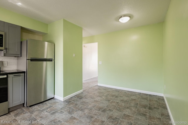 3782 Egan St, Saginaw, MI 48601 - kitchen featuring appliances with stainless steel finishes, dark countertops, gray cabinets, stone finish floors, and tasteful backsplash