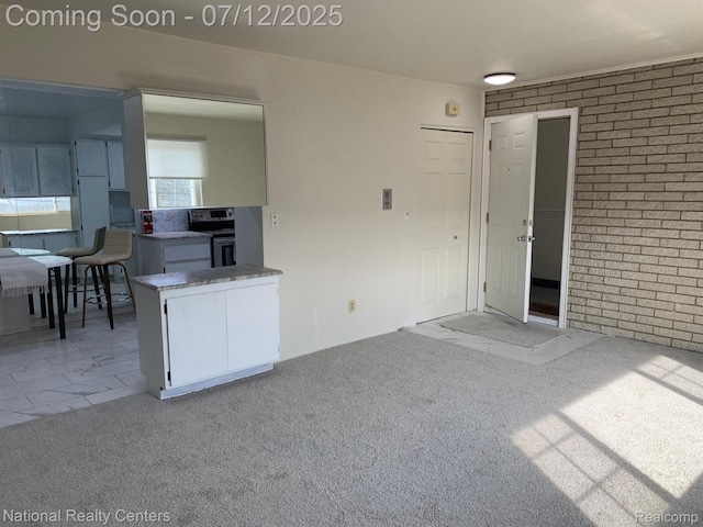 2245 S Walton Blvd Unit 58, Rochester Hills, MI 48309 - kitchen featuring white cabinets, brick wall, stainless steel electric range oven, and light colored carpet