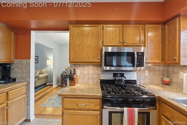 2129 Camelot Dr, Troy, MI 48083 - kitchen with stainless steel appliances, tasteful backsplash, light wood-type flooring, tile counters, and brown cabinetry
