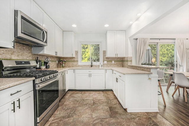 4649 Northview Ave NE, Grand Rapids, MI 49525 - kitchen featuring stainless steel appliances, a peninsula, tasteful backsplash, a breakfast bar area, and white cabinets