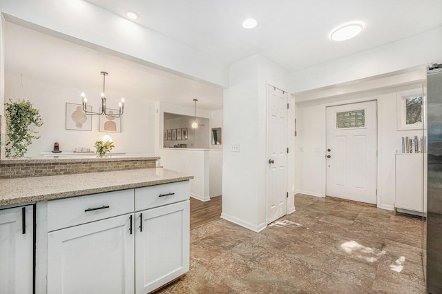 4649 Northview Ave NE, Grand Rapids, MI 49525 - kitchen featuring white cabinetry, light stone countertops, a chandelier, hanging light fixtures, and light marble finish floors