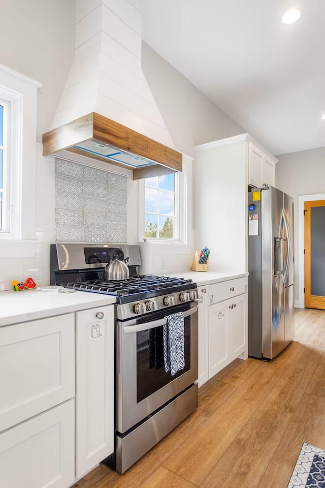 7229 Lakeview Ave, South Haven, MI 49090 - kitchen with appliances with stainless steel finishes, custom range hood, light wood-style flooring, white cabinets, and backsplash