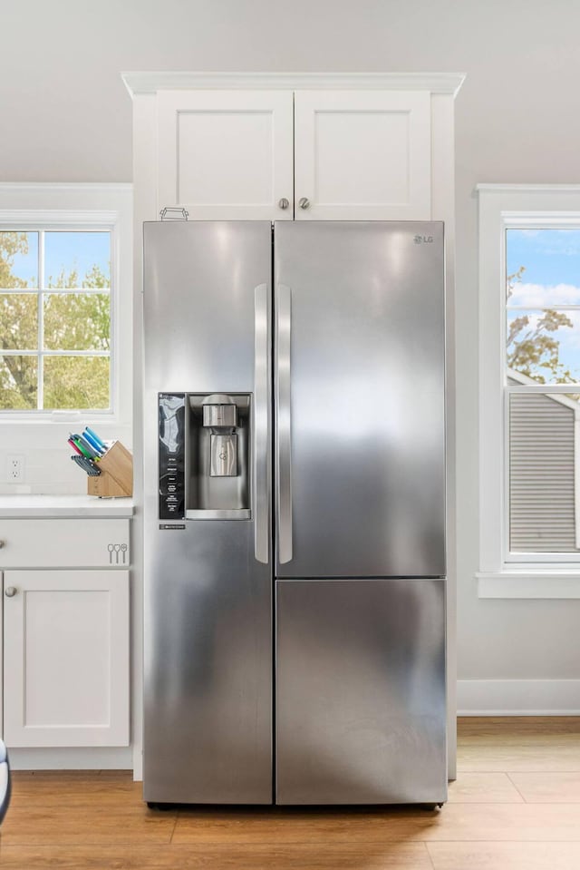 7229 Lakeview Ave, South Haven, MI 49090 - kitchen view of stainless steel refrigerator with ice dispenser, white cabinetry, and light wood-style flooring