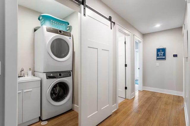 7229 Lakeview Ave, South Haven, MI 49090 - laundry room featuring stacked washer / drying machine, light wood-style flooring, a barn door, and cabinet space