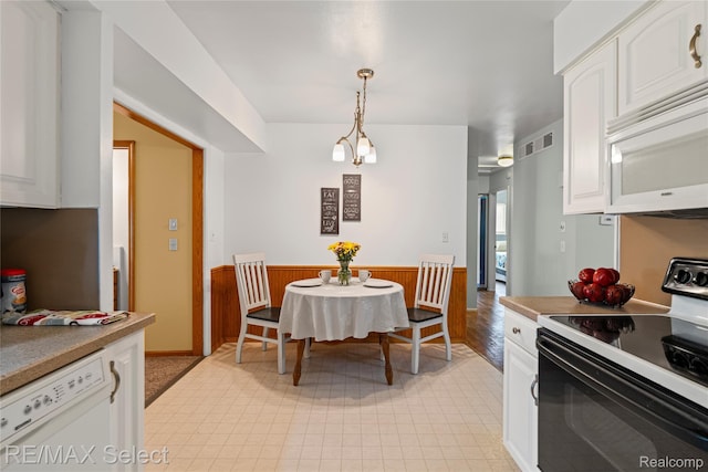 4391 Ashlawn Dr, Flint, MI 48507 - kitchen with white appliances, white cabinets, a wainscoted wall, pendant lighting, and wood walls