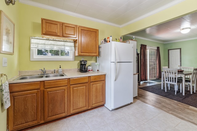 210 S Forbes St, Jackson, MI 49203 - kitchen with freestanding refrigerator, crown molding, light countertops, brown cabinets, and light tile patterned flooring