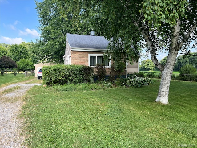 6860 Sheridan Rd, Saginaw, MI 48601 - view of side of home featuring a yard, driveway, a chimney, roof with shingles, and brick siding