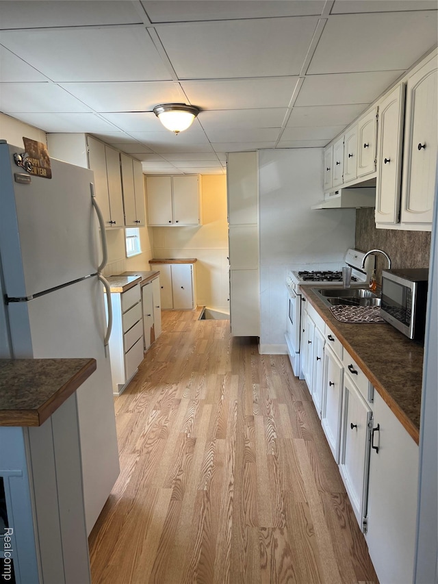 6860 Sheridan Rd, Saginaw, MI 48601 - kitchen with white appliances, under cabinet range hood, dark countertops, a drop ceiling, and light wood-type flooring