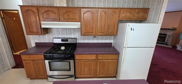 19270 W Brant Rd, Brant, MI 48614 - kitchen featuring freestanding refrigerator, wallpapered walls, under cabinet range hood, stainless steel range with gas stovetop, and dark countertops