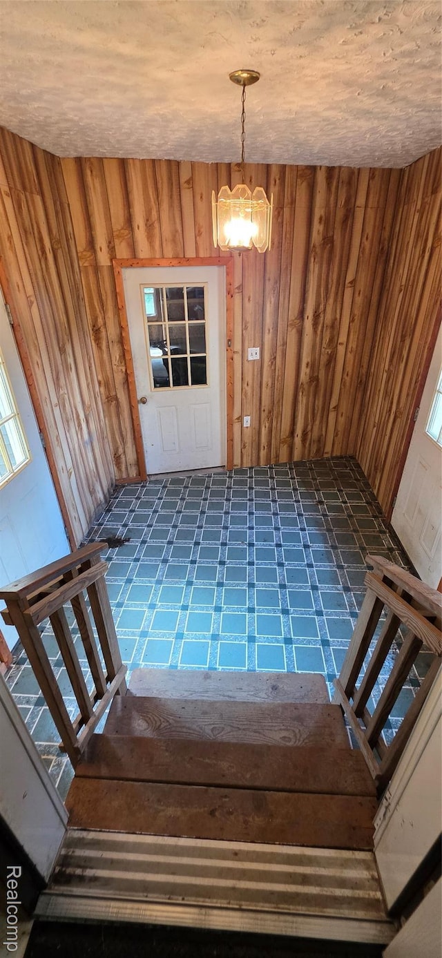 19270 W Brant Rd, Brant, MI 48614 - stairs with tile patterned floors, wooden walls, and a chandelier