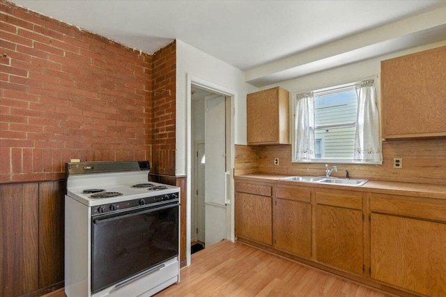 2251 Gardner Ave, Berkley, MI 48072 - kitchen featuring white electric stove, light countertops, light wood-style flooring, brick wall, and brown cabinets