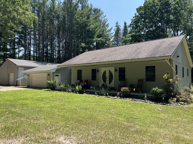2564 Bialik Rd, Manistee, MI 49660 - ranch-style home with a front lawn, roof with shingles, and a garage