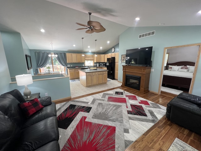 2564 Bialik Rd, Manistee, MI 49660 - living room featuring light wood-style flooring, vaulted ceiling, a ceiling fan, a glass covered fireplace, and recessed lighting