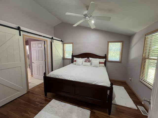 2564 Bialik Rd, Manistee, MI 49660 - bedroom with vaulted ceiling, a barn door, wood finished floors, and ceiling fan