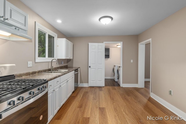911 Baldwin St SE, Grand Rapids, MI 49506 - kitchen featuring appliances with stainless steel finishes, washer and dryer, under cabinet range hood, white cabinets, and dark countertops