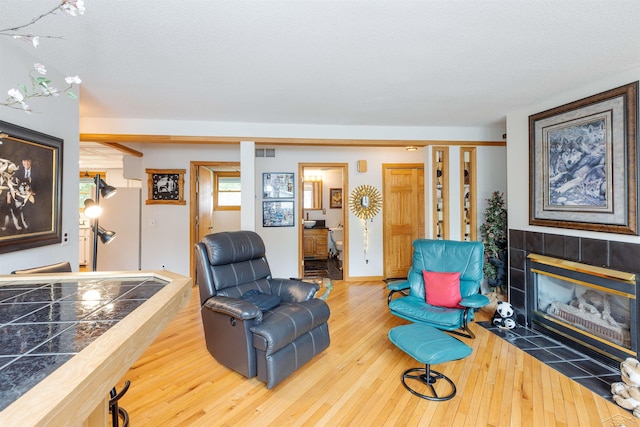 5370 N Lake Sanford Rd, Sanford, MI 48657 - living area featuring hardwood / wood-style flooring, a tiled fireplace, and a textured ceiling