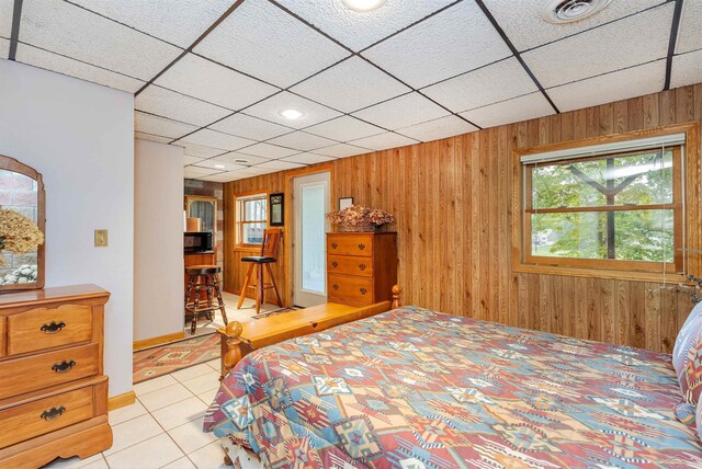5370 N Lake Sanford Rd, Sanford, MI 48657 - bedroom with wood walls, light tile patterned floors, and a drop ceiling