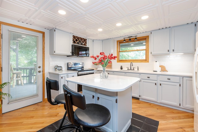 5370 N Lake Sanford Rd, Sanford, MI 48657 - kitchen with stainless steel electric stove, black microwave, a kitchen breakfast bar, light countertops, and recessed lighting