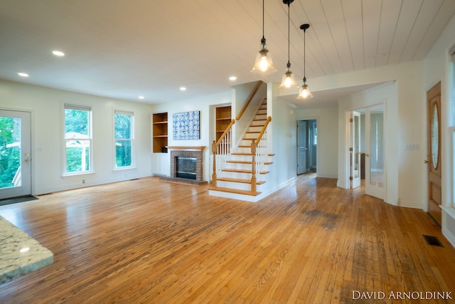 401 Erin Isle Ct, Holland, MI 49424 - unfurnished living room featuring a fireplace, light wood-style floors, stairs, recessed lighting, and wooden ceiling
