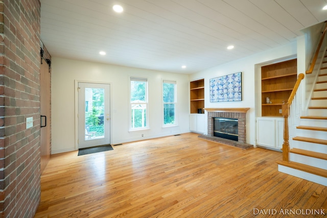 401 Erin Isle Ct, Holland, MI 49424 - unfurnished living room featuring light wood finished floors, stairway, a fireplace, built in features, and recessed lighting