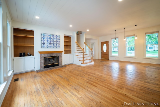 401 Erin Isle Ct, Holland, MI 49424 - unfurnished living room with light wood-style flooring, a brick fireplace, stairway, built in shelves, and recessed lighting