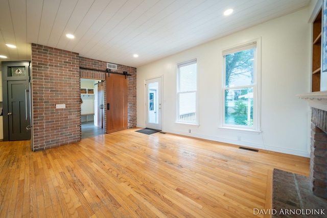 401 Erin Isle Ct, Holland, MI 49424 - unfurnished living room with a barn door, brick wall, light wood finished floors, a fireplace with flush hearth, and wood ceiling