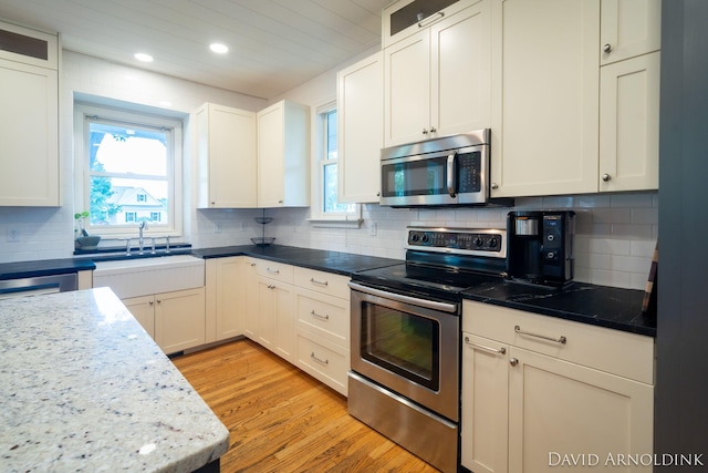 401 Erin Isle Ct, Holland, MI 49424 - kitchen with stainless steel appliances, recessed lighting, decorative backsplash, white cabinets, and light wood-style floors
