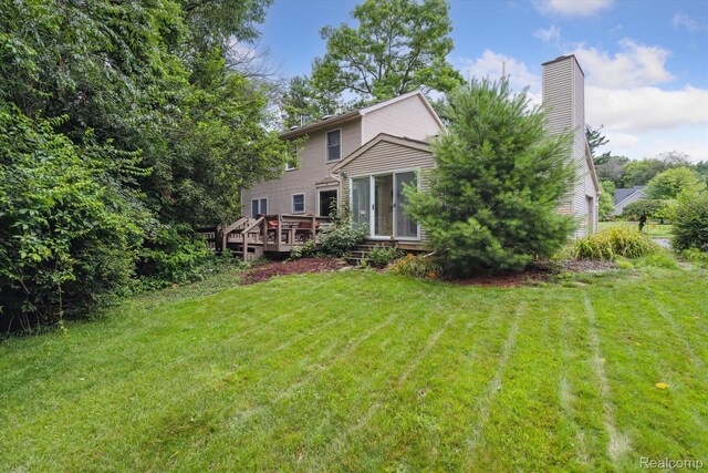 7740 Athlone Dr, Brighton, MI 48116 - back of property with a deck, a yard, a sunroom, and a chimney