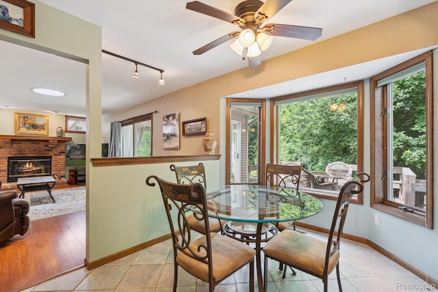 7740 Athlone Dr, Brighton, MI 48116 - dining area with track lighting, a brick fireplace, ceiling fan, and light tile patterned floors