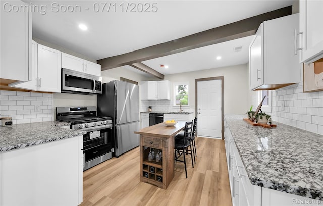 313 W Harwood Ave, Madison Heights, MI 48071 - kitchen featuring appliances with stainless steel finishes, tasteful backsplash, light wood-style floors, white cabinetry, and light stone countertops