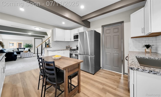 313 W Harwood Ave, Madison Heights, MI 48071 - kitchen with stainless steel appliances, white cabinets, light wood-style flooring, light stone counters, and tasteful backsplash