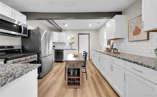 313 W Harwood Ave, Madison Heights, MI 48071 - kitchen featuring appliances with stainless steel finishes, light wood finished floors, white cabinets, dark stone counters, and decorative backsplash