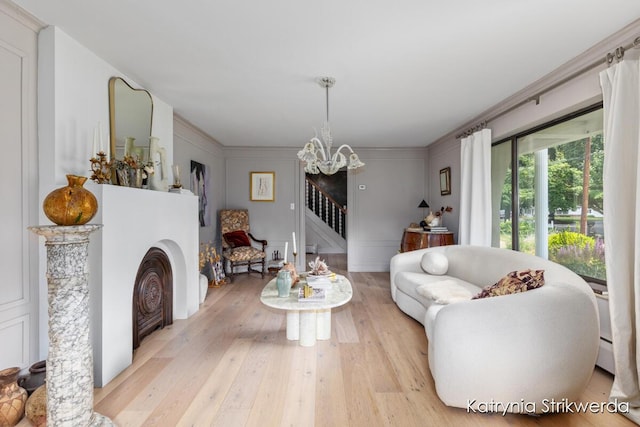 1217 El Camino Dr NW, Grand Rapids, MI 49504 - living room featuring stairway, a chandelier, light wood-style floors, a decorative wall, and ornamental molding