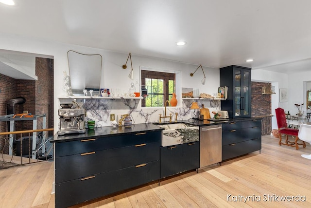1217 El Camino Dr NW, Grand Rapids, MI 49504 - kitchen featuring stainless steel dishwasher, light wood finished floors, open shelves, dark countertops, and a wood stove