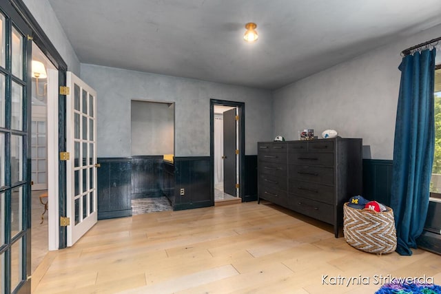 1217 El Camino Dr NW, Grand Rapids, MI 49504 - bedroom with wood finished floors, wainscoting, and french doors