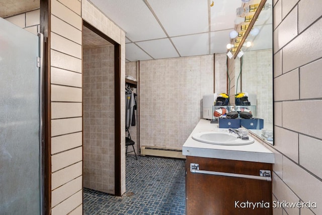 1217 El Camino Dr NW, Grand Rapids, MI 49504 - bathroom with a baseboard heating unit, tile walls, vanity, tile patterned flooring, and a drop ceiling